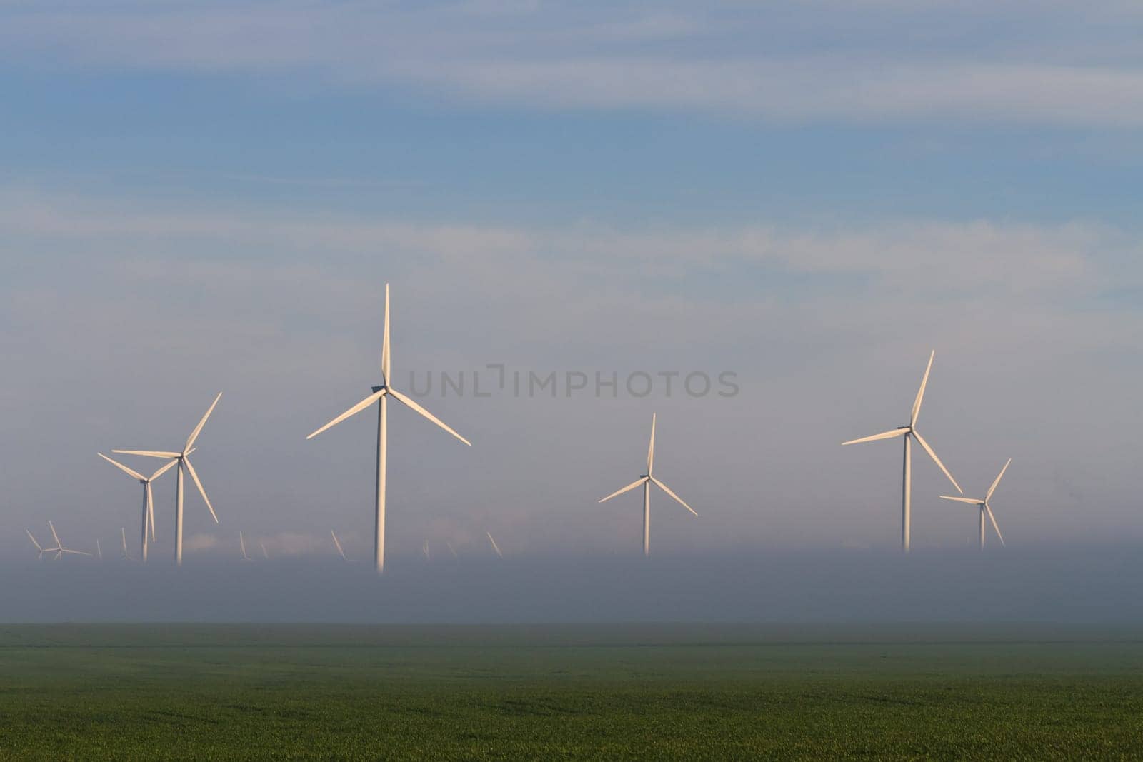 wind power turbines on a hill in fog