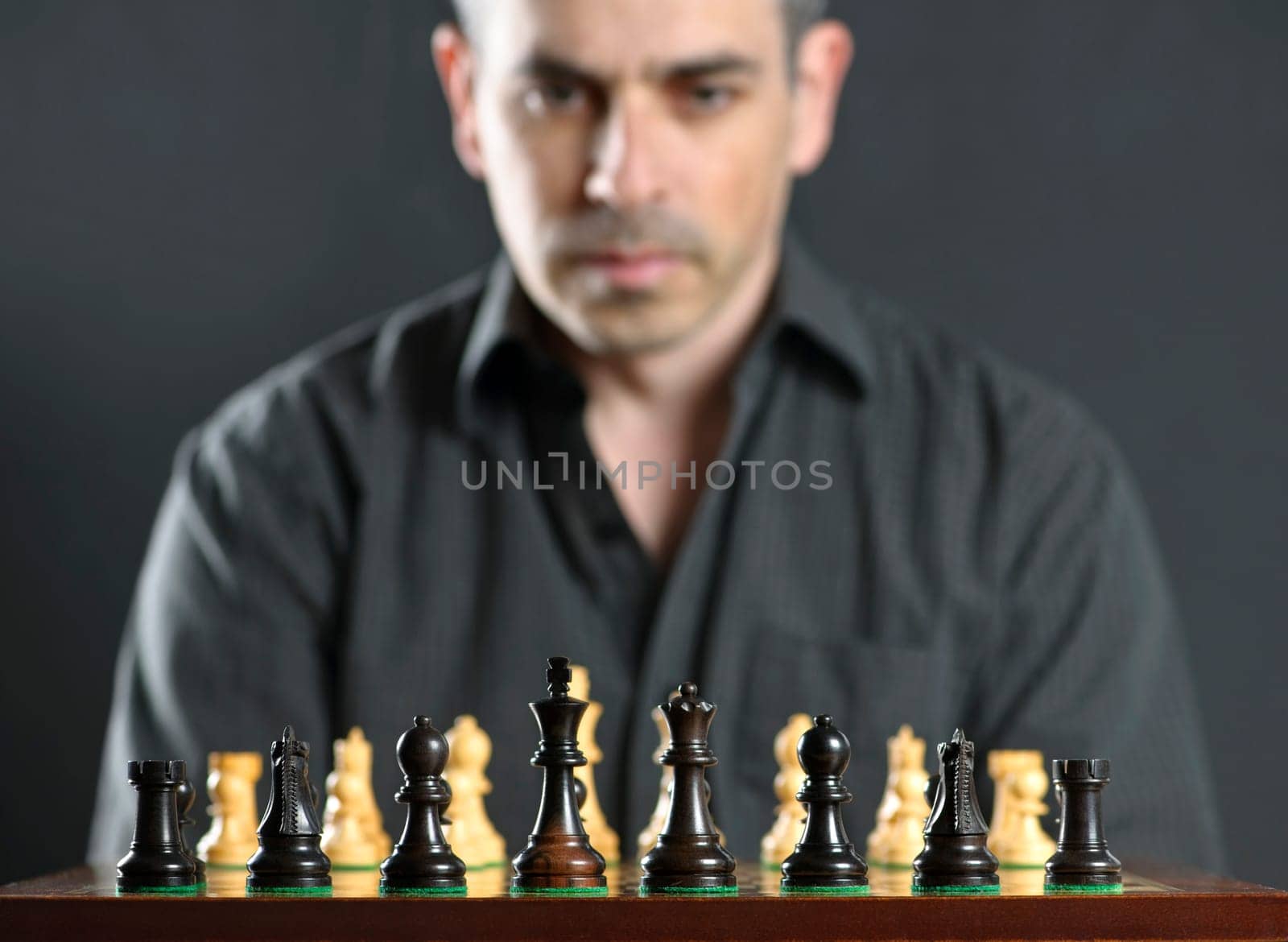 Man looking at wooden chess board thinking about first move