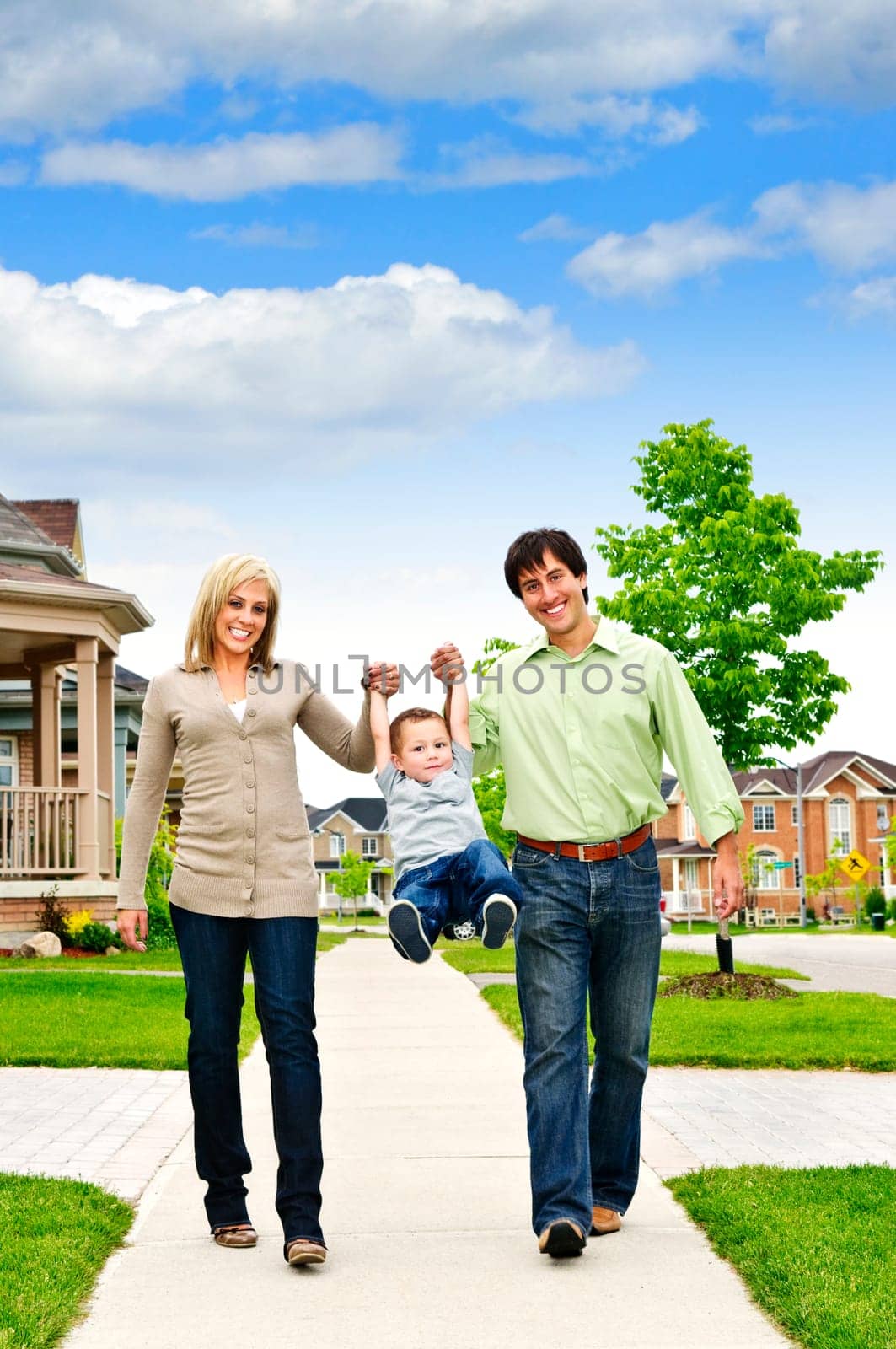 Young happy family playing with son on sidewalk