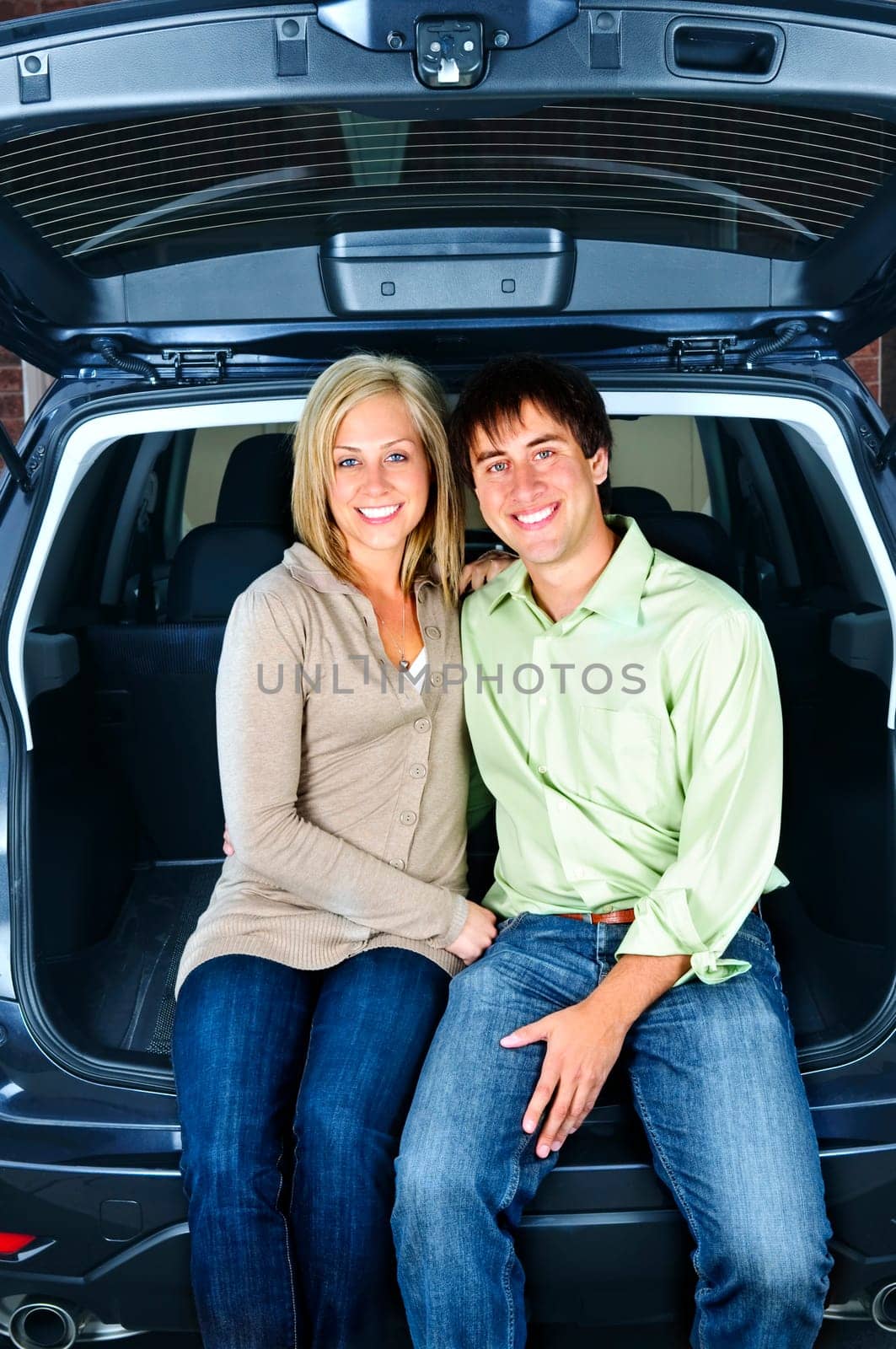 Happy young couple sitting at back of car