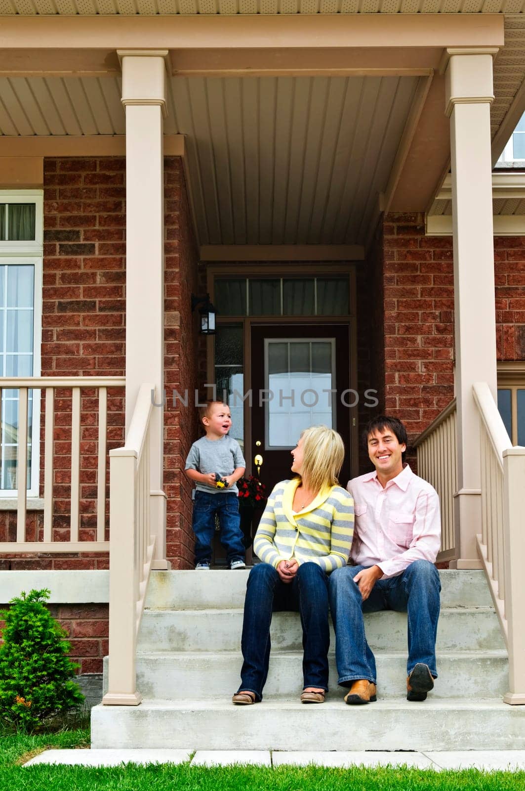 Young family sitting on front steps of house