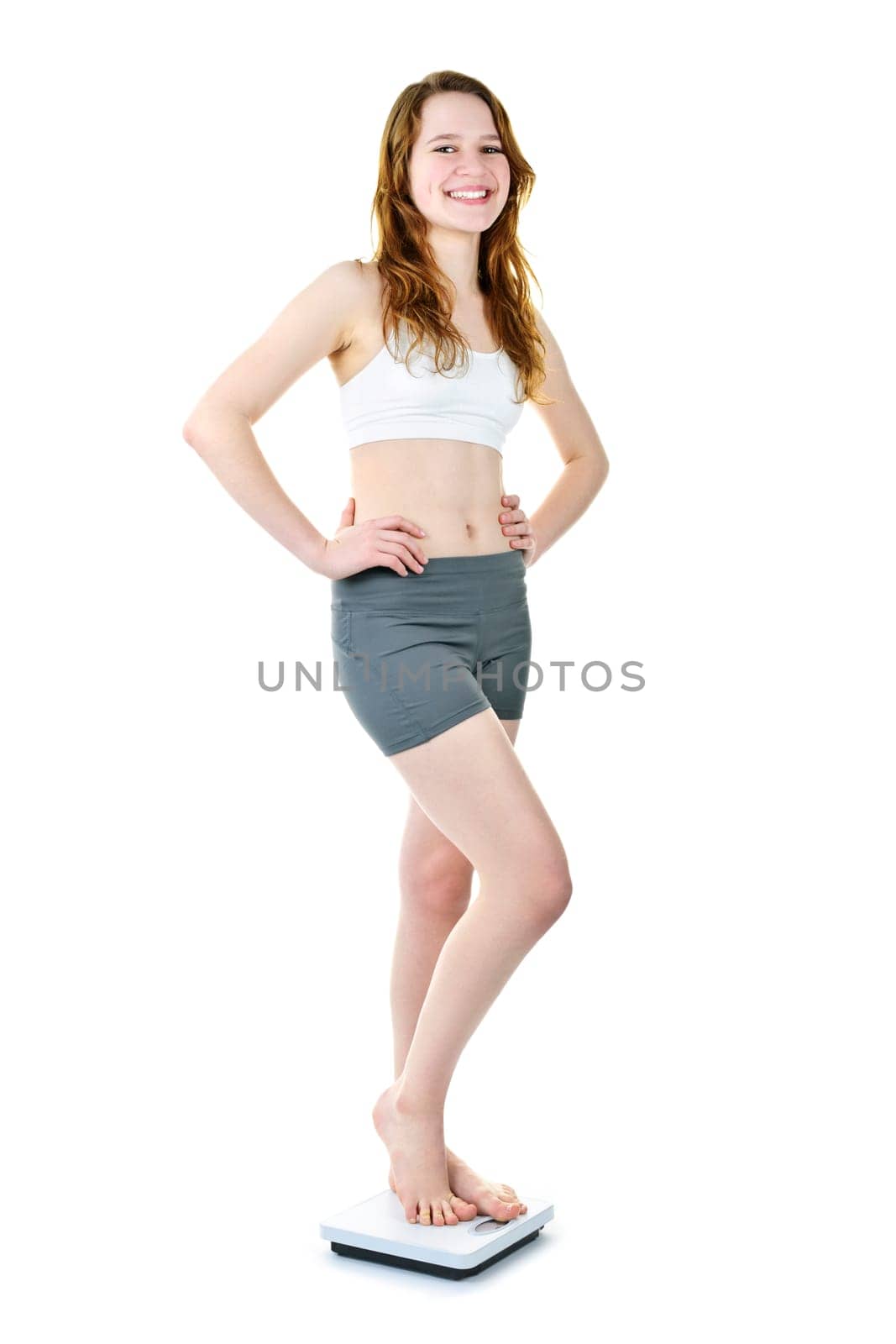 Smiling fit young woman standing on bathroom scale isolated on white
