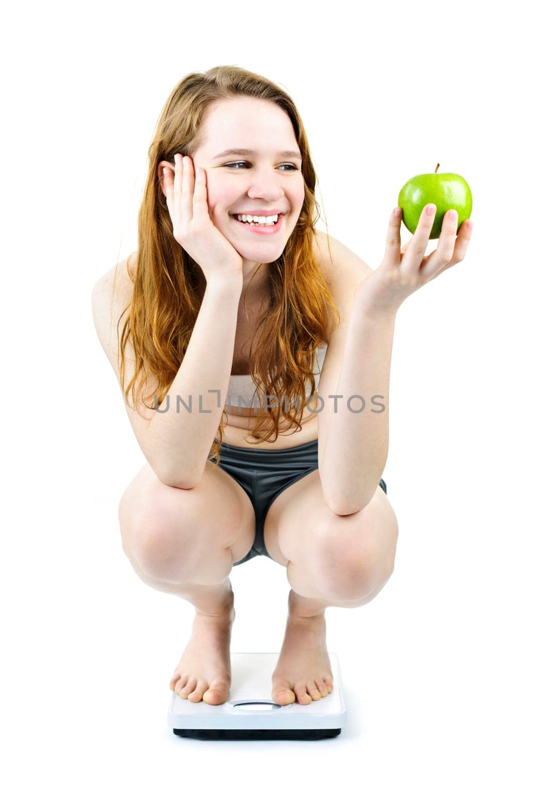 Healthy happy young woman holding apple on bathroom scale isolated on white