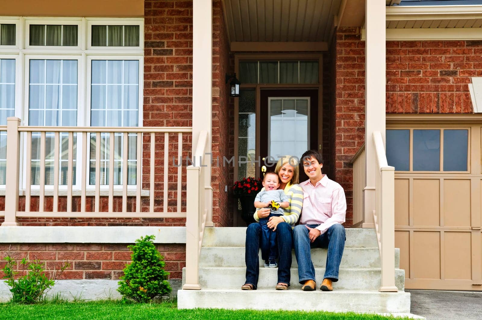 Young family sitting on front steps of house