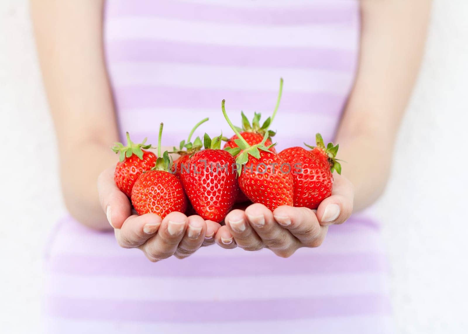 Girl hold fresh strawberries. Shallow DOF, focus on strawberries.