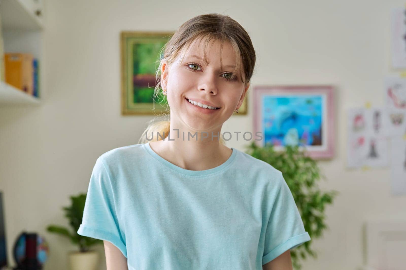 Close up portrait of preteen girl 12, 13, 14 years old, smiling girl looking at camera inside home room
