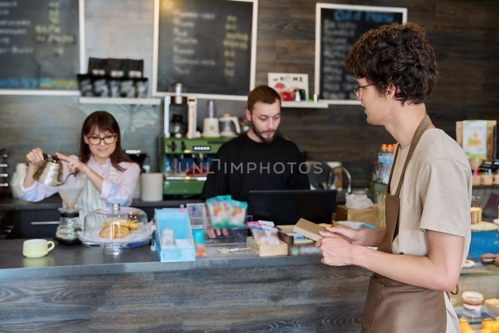 Coffee shop workers, a young guy in an apron in focus. Small business cafe cafeteria coffee house, job, work, staff people concept