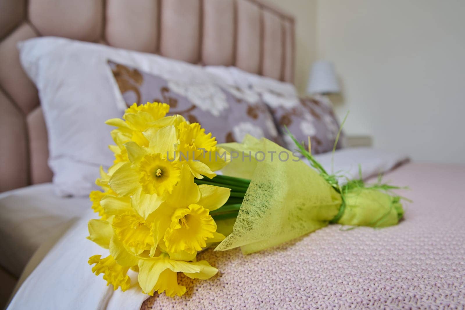 Bouquet of yellow flowers on bed in bedroom by VH-studio