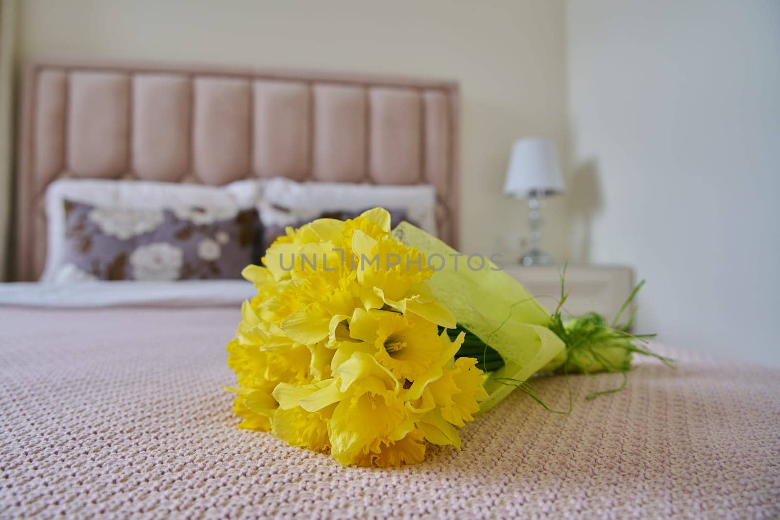 Bouquet of yellow flowers on bed in bedroom by VH-studio