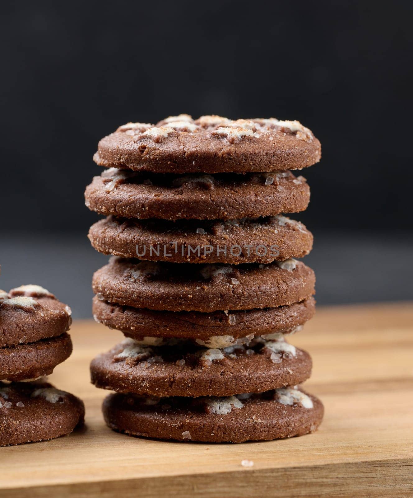 Stack of round chocolate cookies on a black background by ndanko