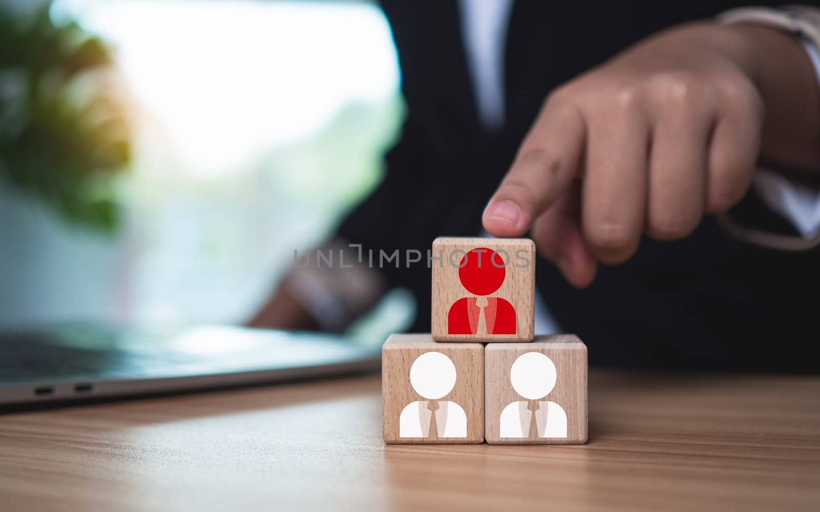Wooden blocks with printed manager icons selected by businessmen to express human resource management and leadership concepts.