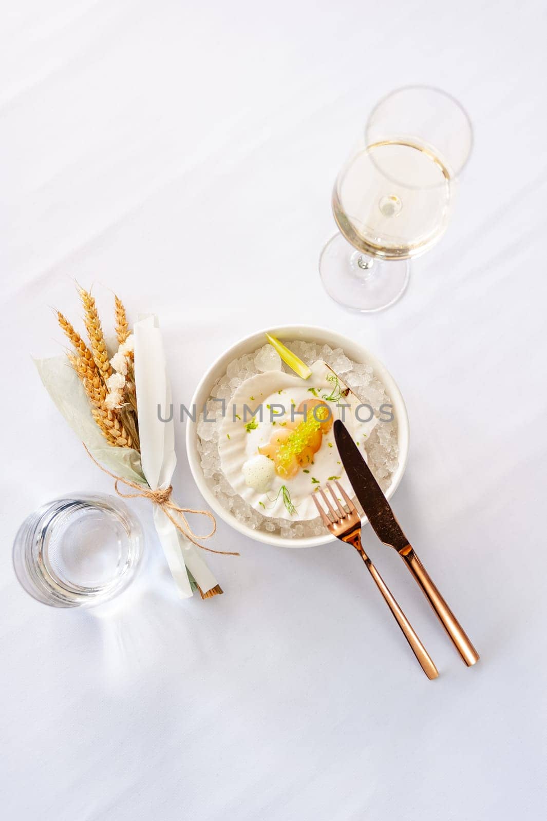 Scallop in sauce with flying fish caviar on a shell on ice in a restaurant. High quality photo