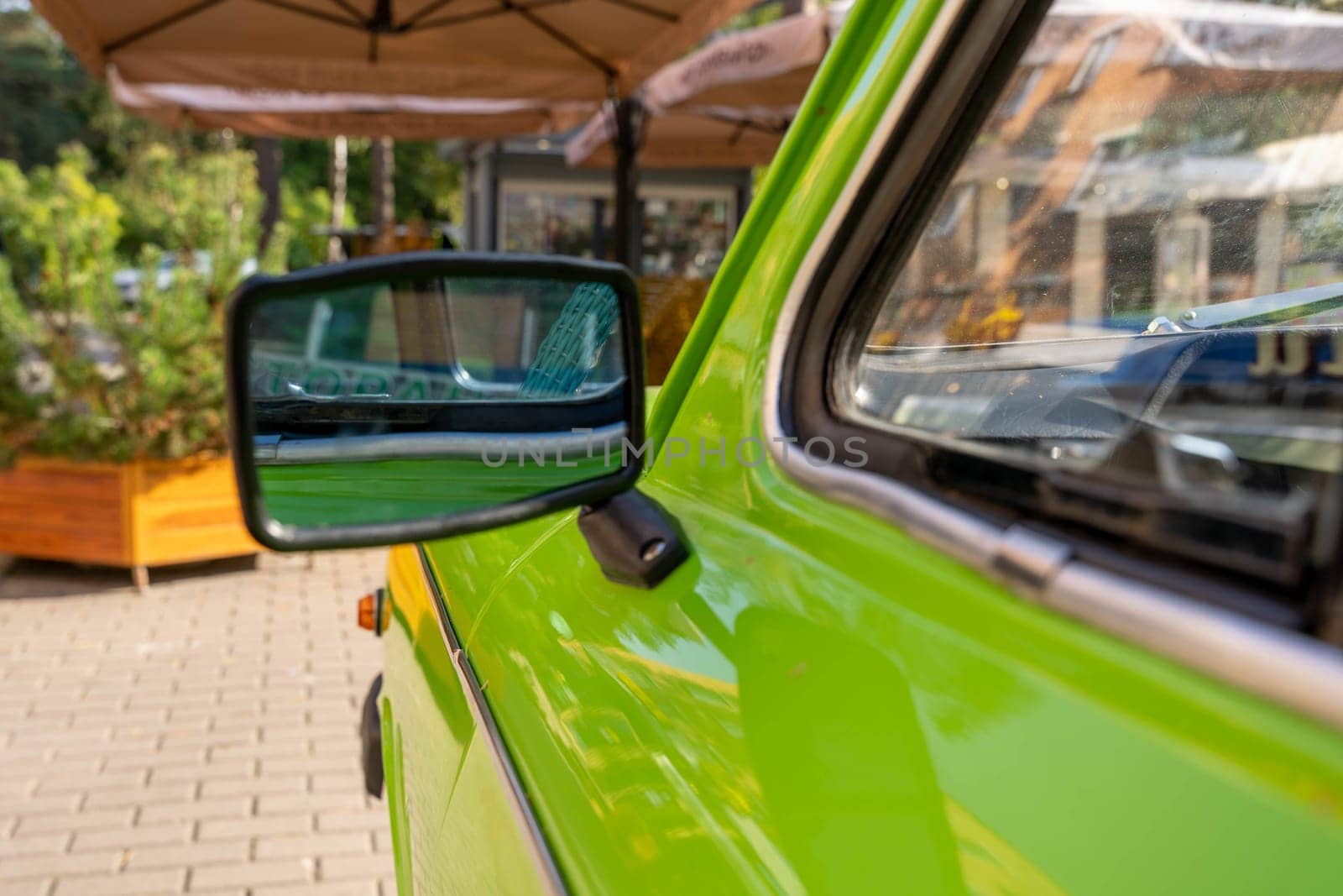 the side rearview mirror of an old classic car is light green. Details of retro cars. View of the city street cafe