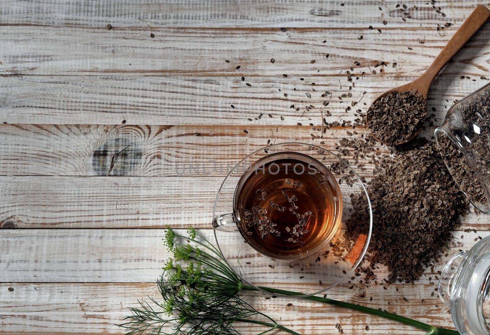 Medicinal tea using dried dill seeds in a cup on a natural wooden table.
