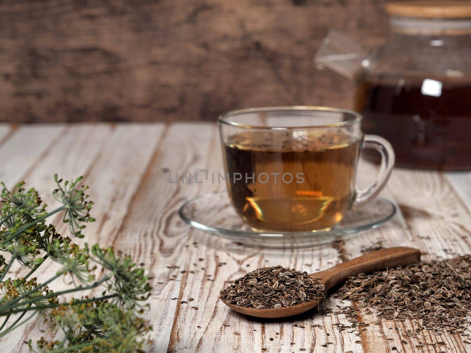 Medicinal tea using dried dill seeds in a cup and teapot on a natural wooden table. The concept of the usefulness of dill. by TatianaPink