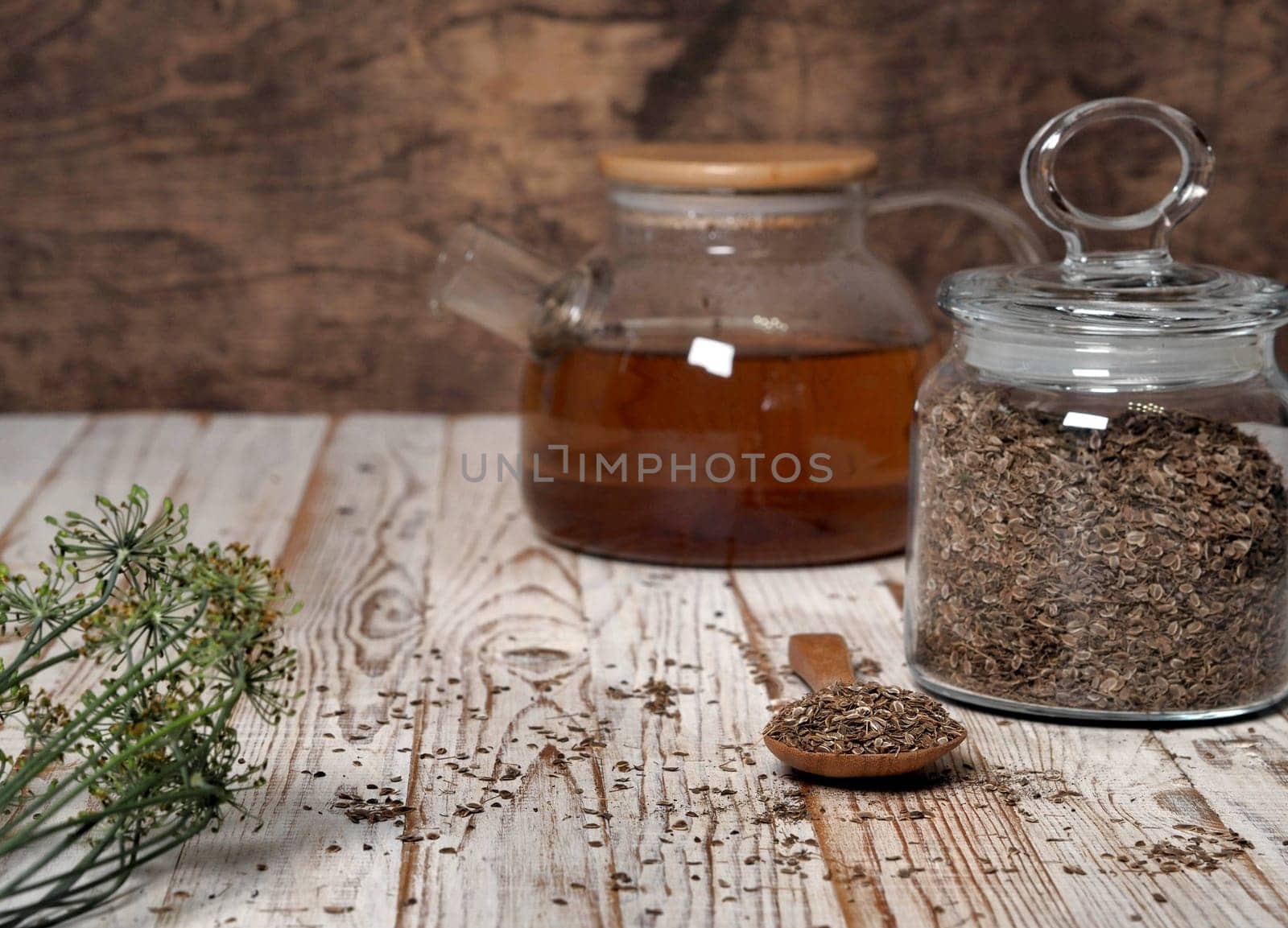 The concept of the usefulness of dill. Medicinal tea using dried dill seeds in a cup and teapot on a natural wooden table. by TatianaPink
