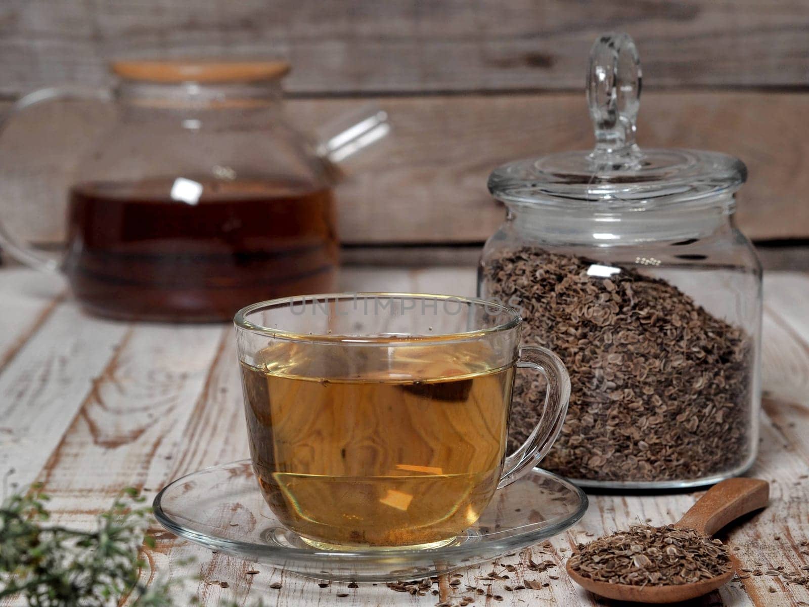 The concept of the usefulness of dill. Medicinal tea using dried dill seeds in a cup and teapot on a natural wooden table