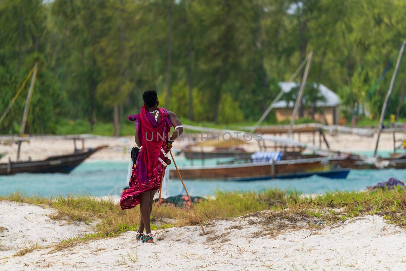 View from behind of a Zanzibar Masai dressed in traditional clothing as he stands looking at the sea at sunny day, zanzibar , Tanzania