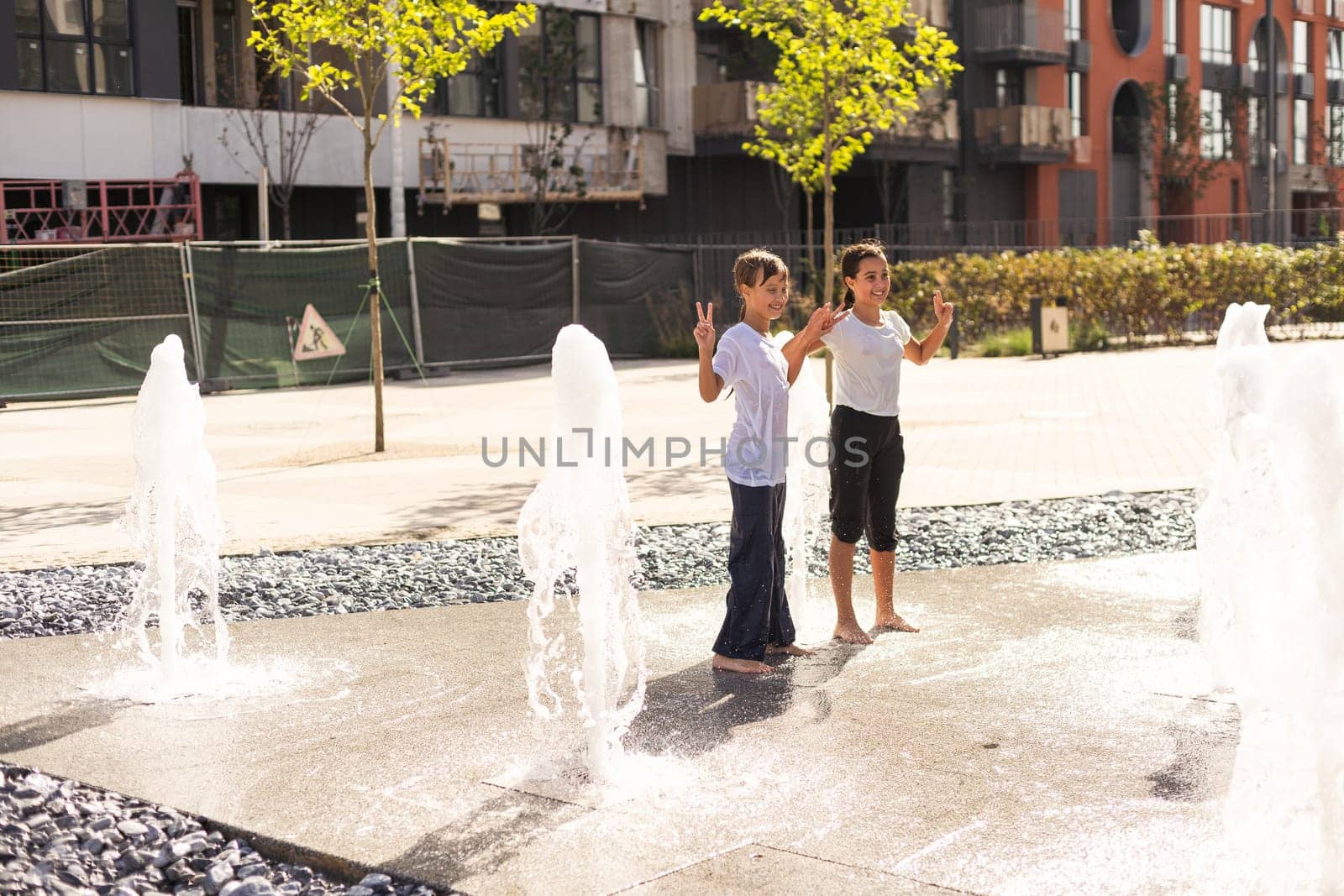 life of children in a modern city - little girl having fun with fountains. High quality photo