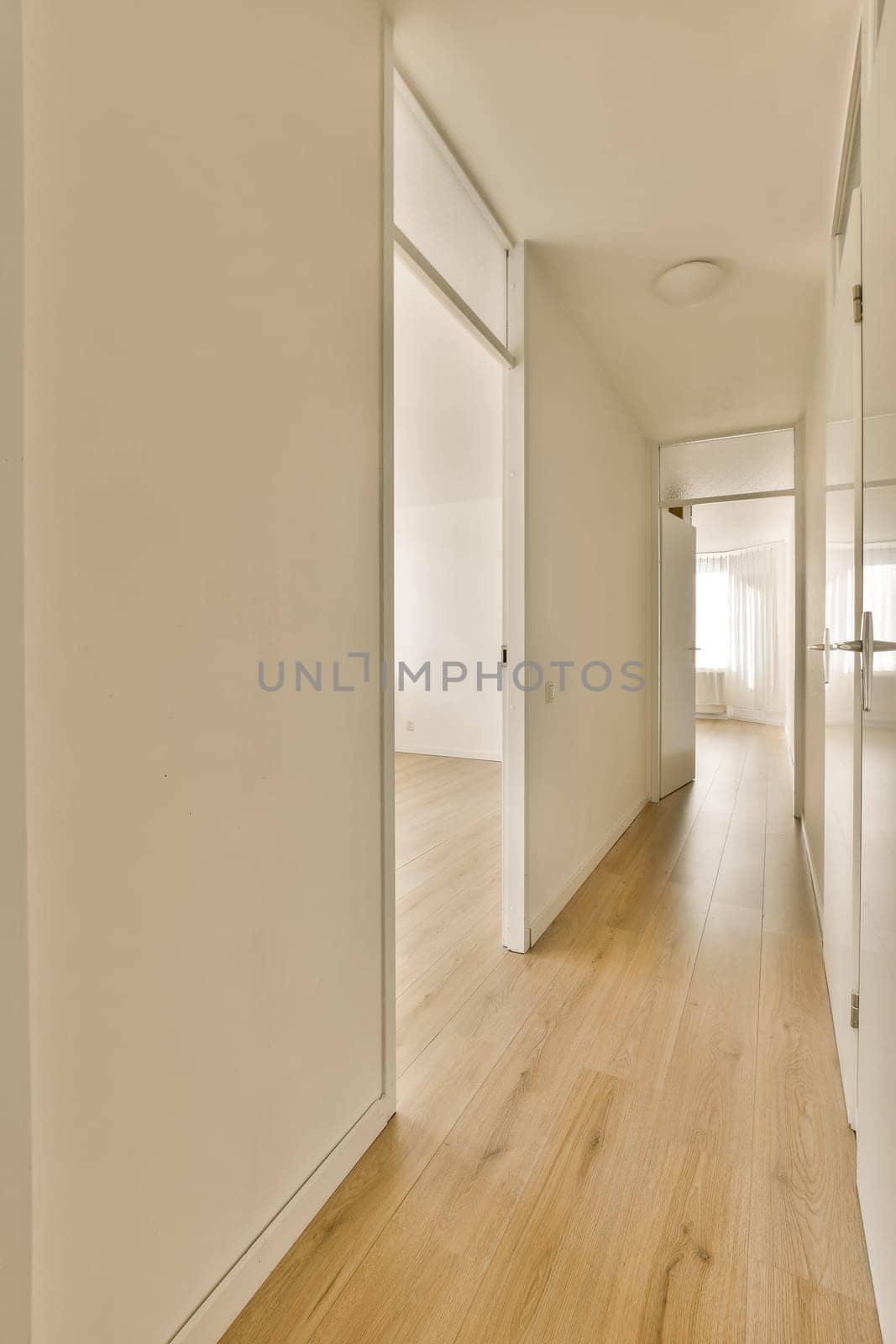 an empty room with white walls and wood flooring on the right side of the room, there is a door leading to another