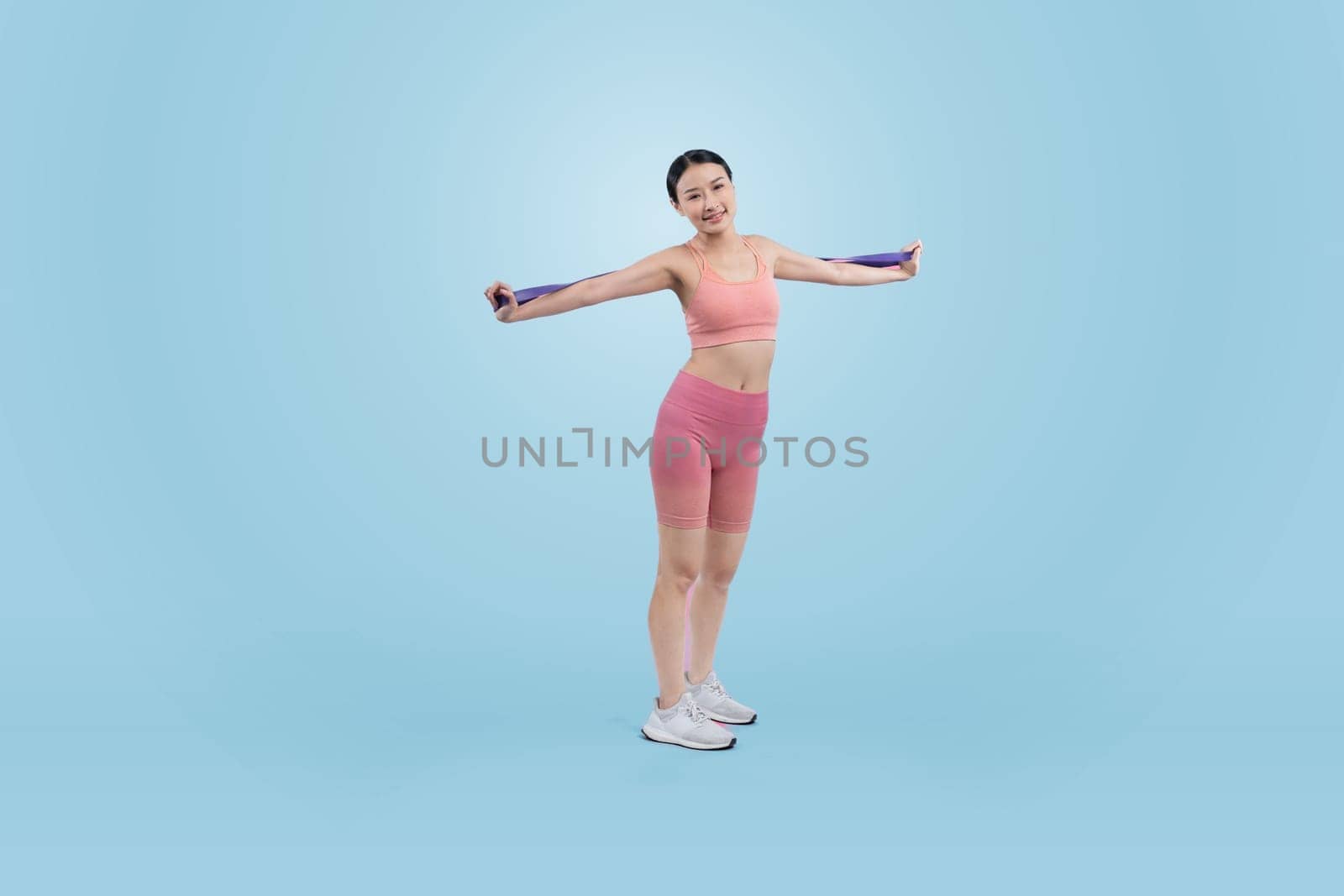 Vigorous energetic woman in sportswear portrait stretching resistance sport band. Young athletic asian woman strength and endurance training session workout routine concept on isolated background.