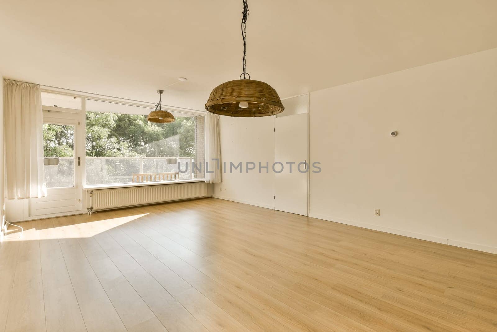 an empty living room with wood flooring and large windows looking out onto the garden area in the back yard