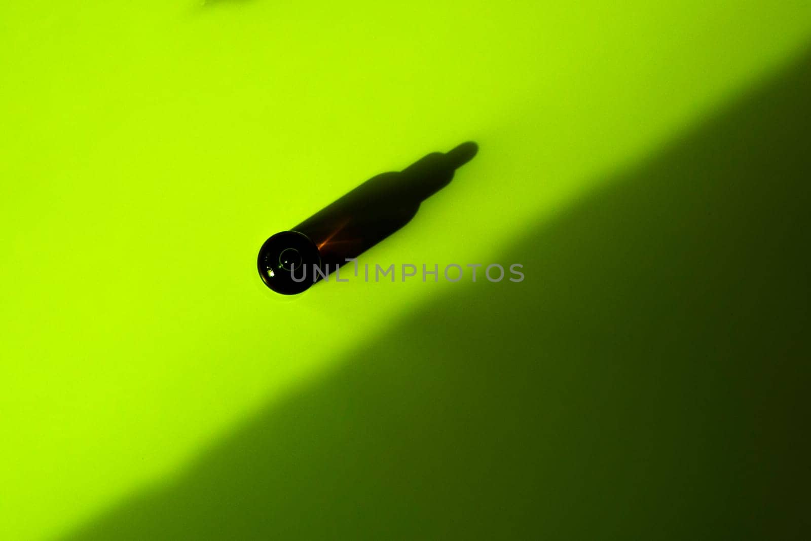 Top view with shadows Brown glass bottle with cosmetic product and pipette,bright green background with dark. Container for oils, gel, acids