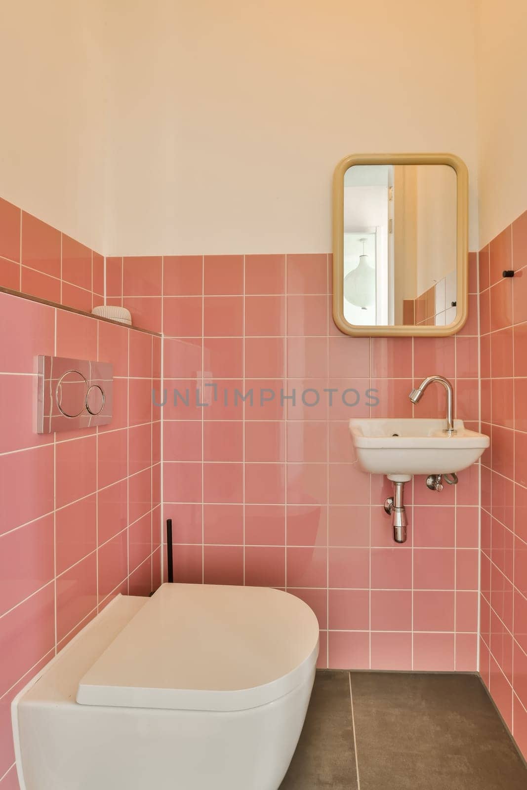 a bathroom with pink tiles on the walls, and a white toilet bowl in the corner next to the sink
