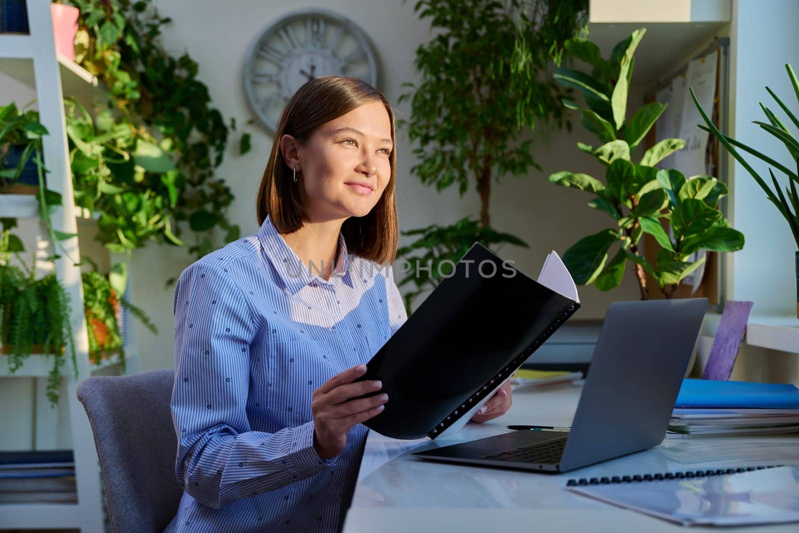 Portrait of young woman sitting at home at desk with computer laptop by VH-studio