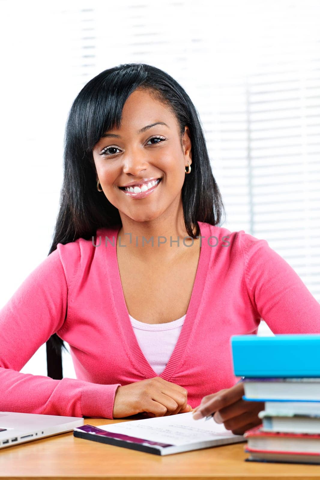 Smiling young black female student studying at desk