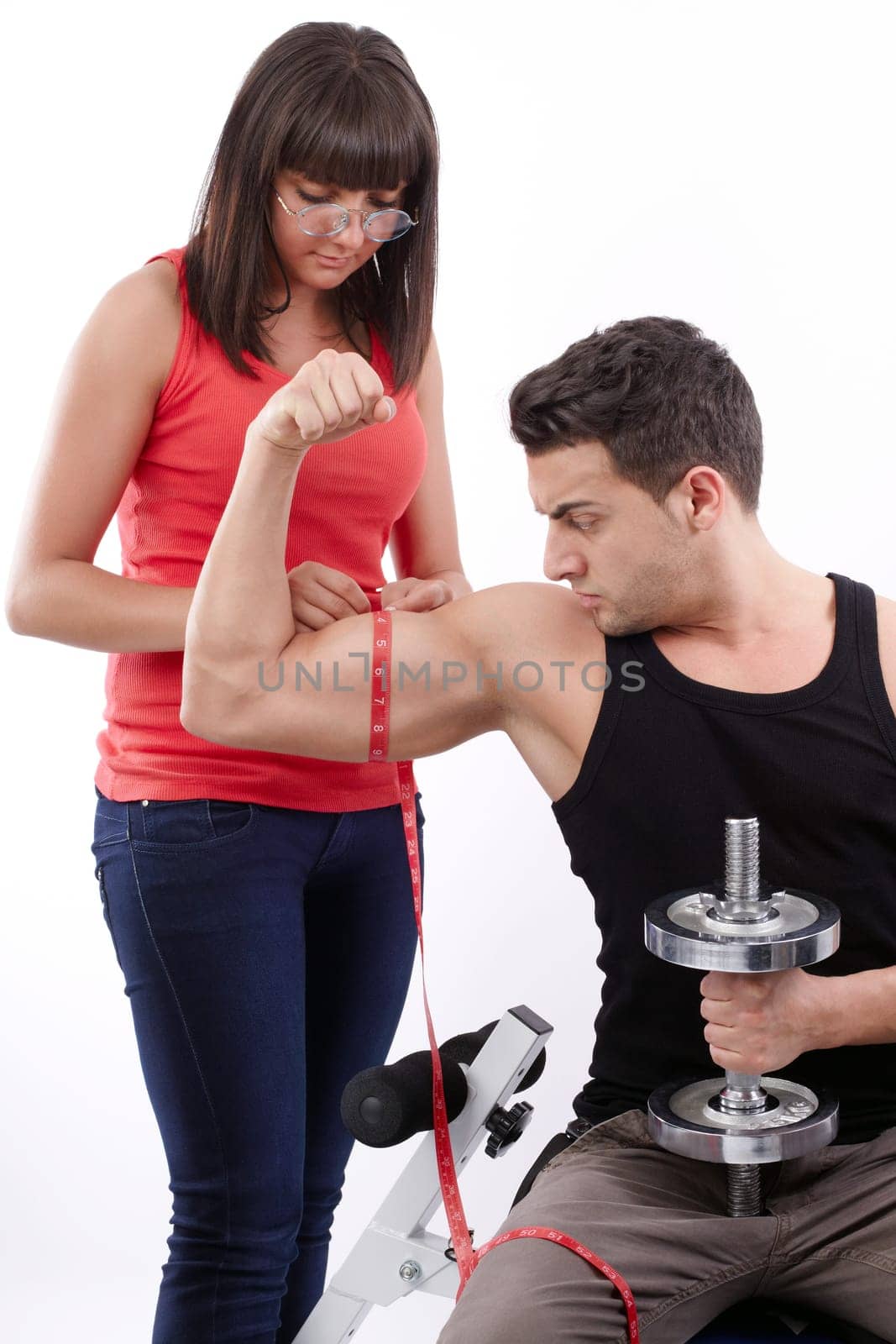 Pretty young woman measuring the biceps of handsome muscular man