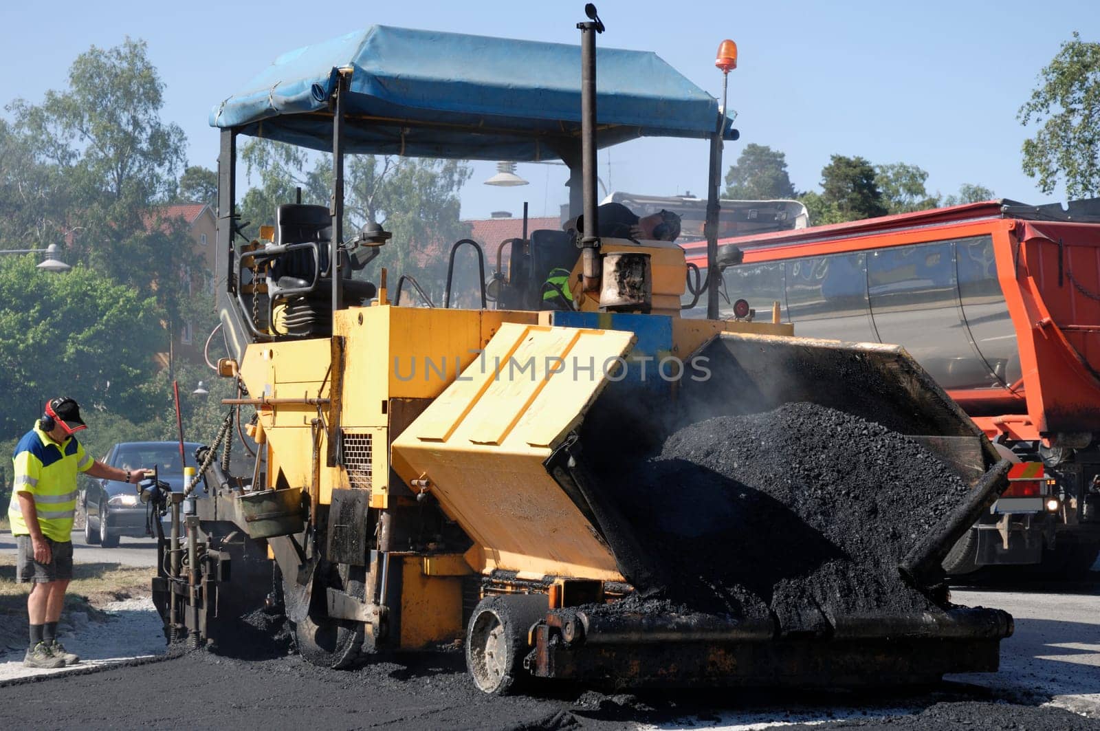large asphalt paving machinery at works, operator standing on ground