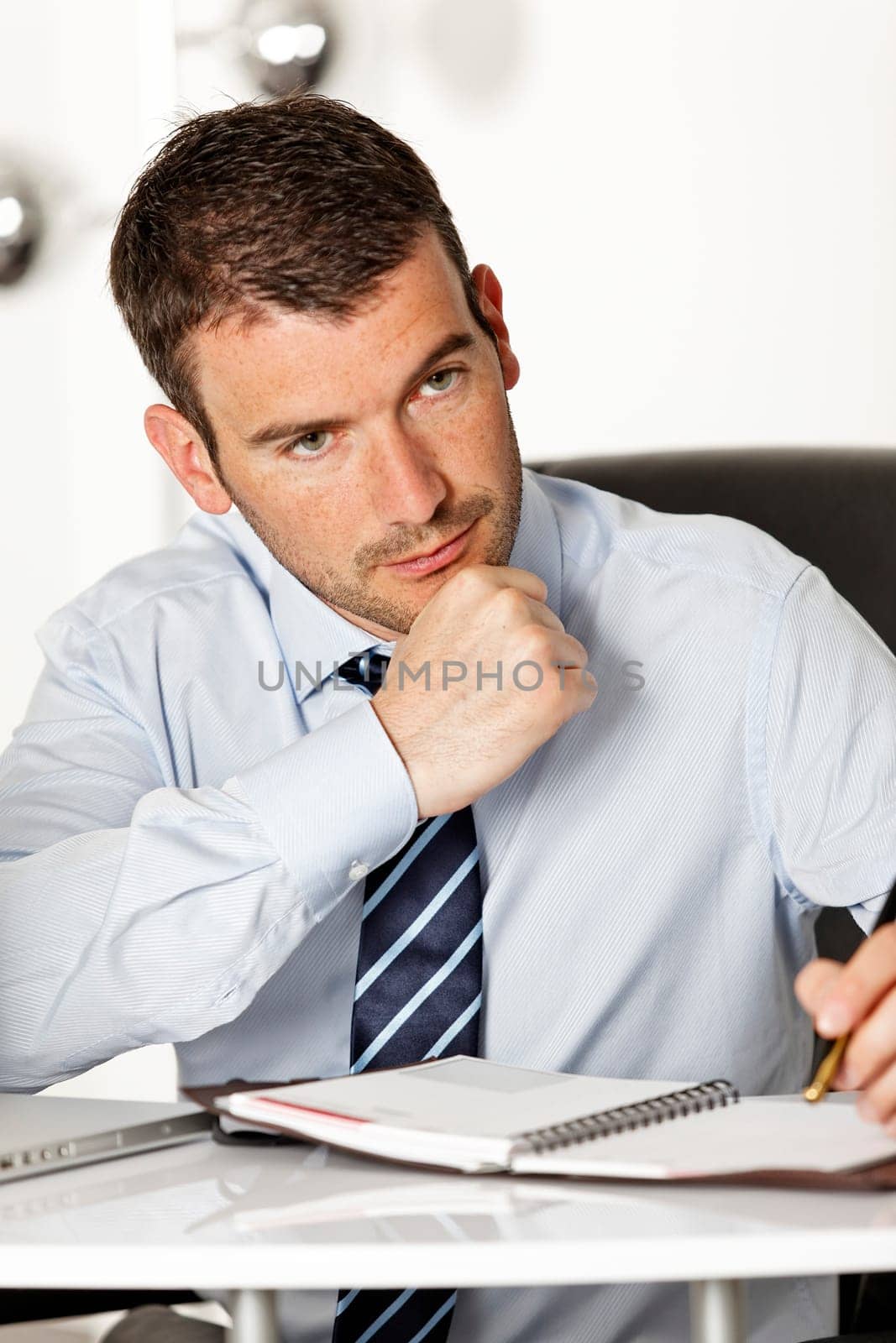 young pensive businessman in office with pen
