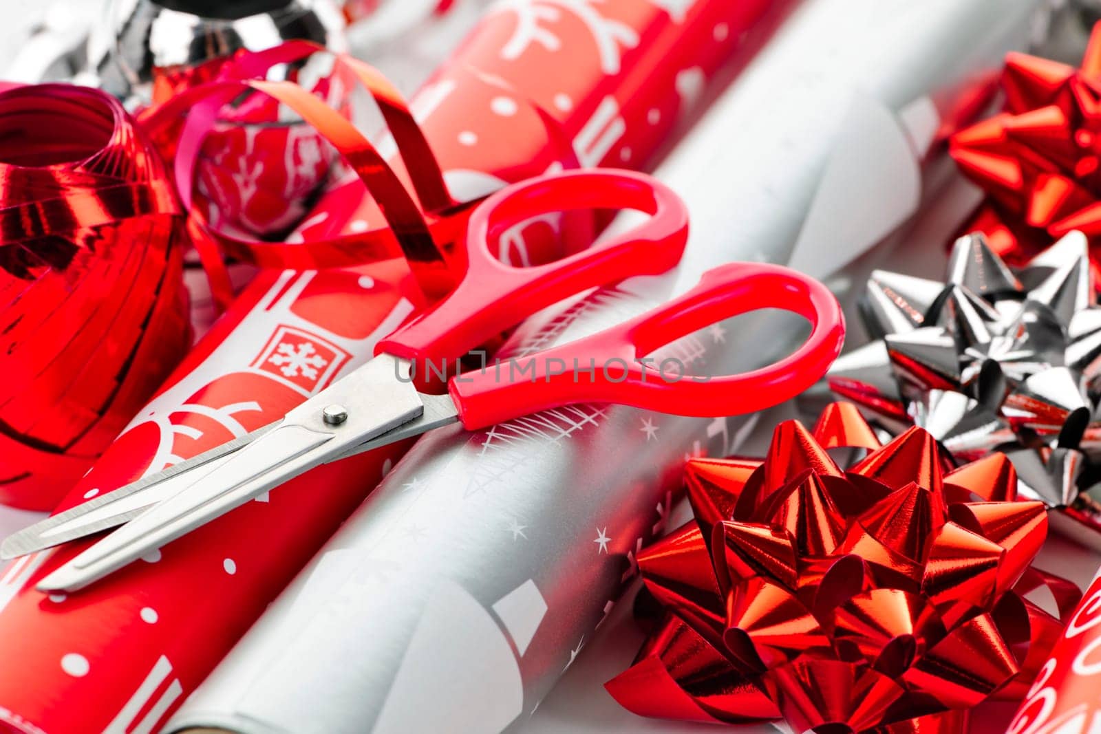 Rolls of Christmas wrapping paper with ribbons, bows and scissors