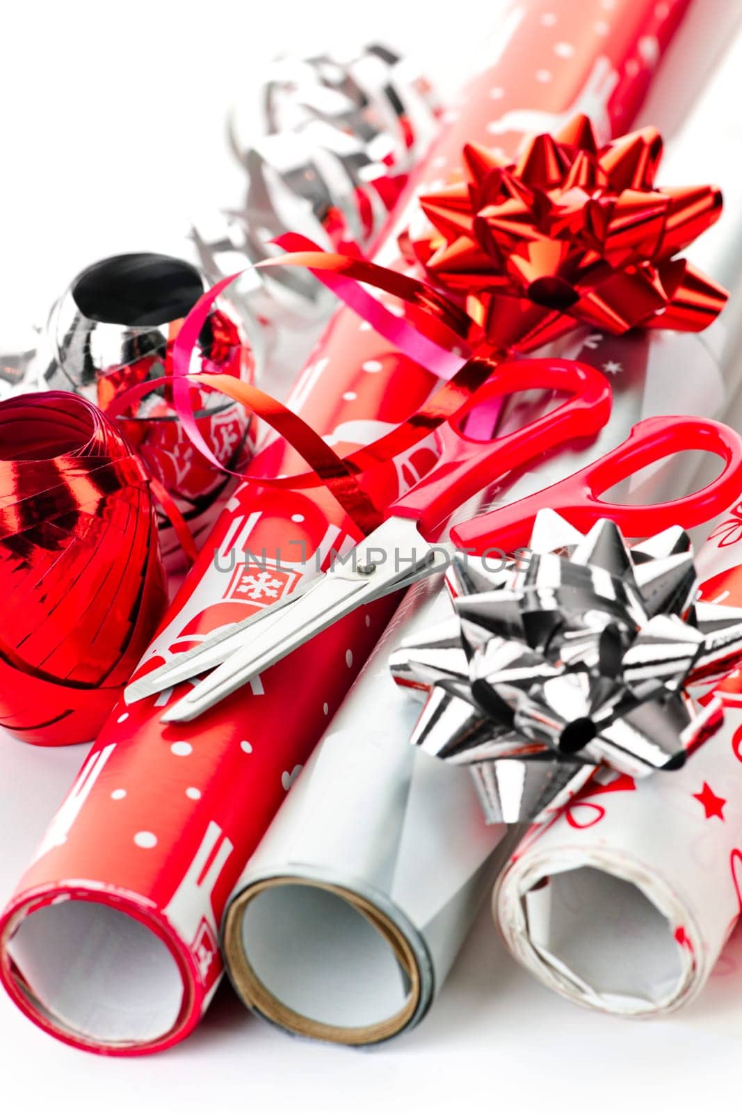Rolls of Christmas wrapping paper with ribbons, bows and scissors