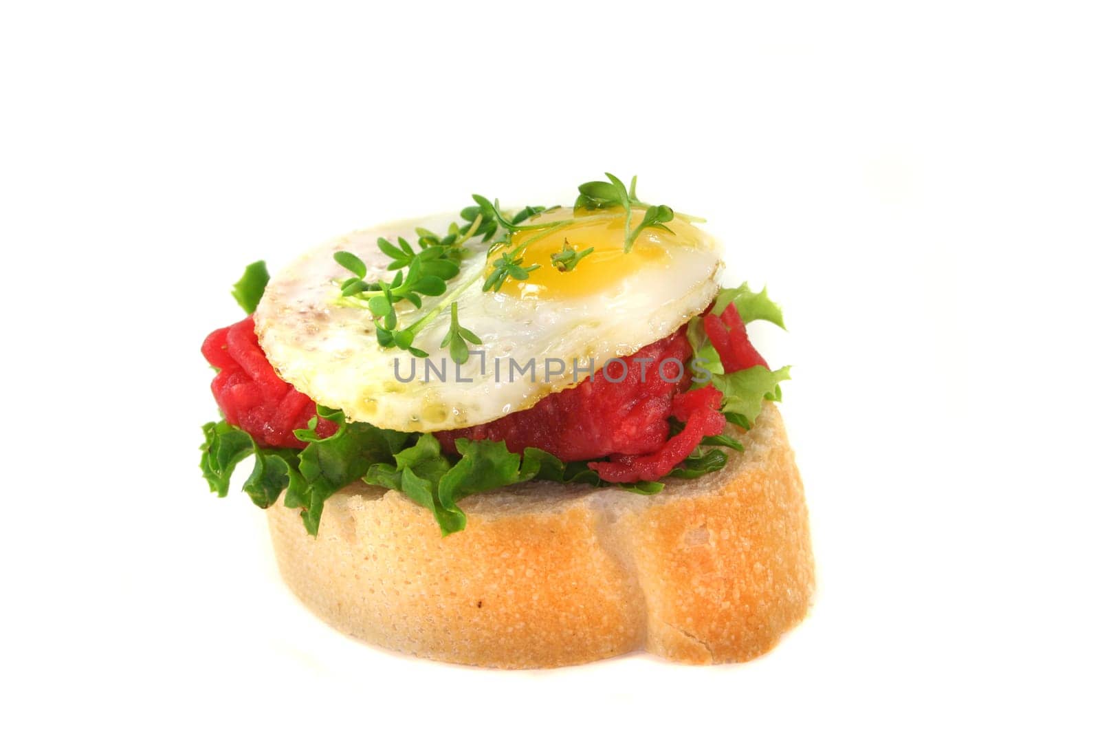 a slice of baguette with tartare and fried quail egg