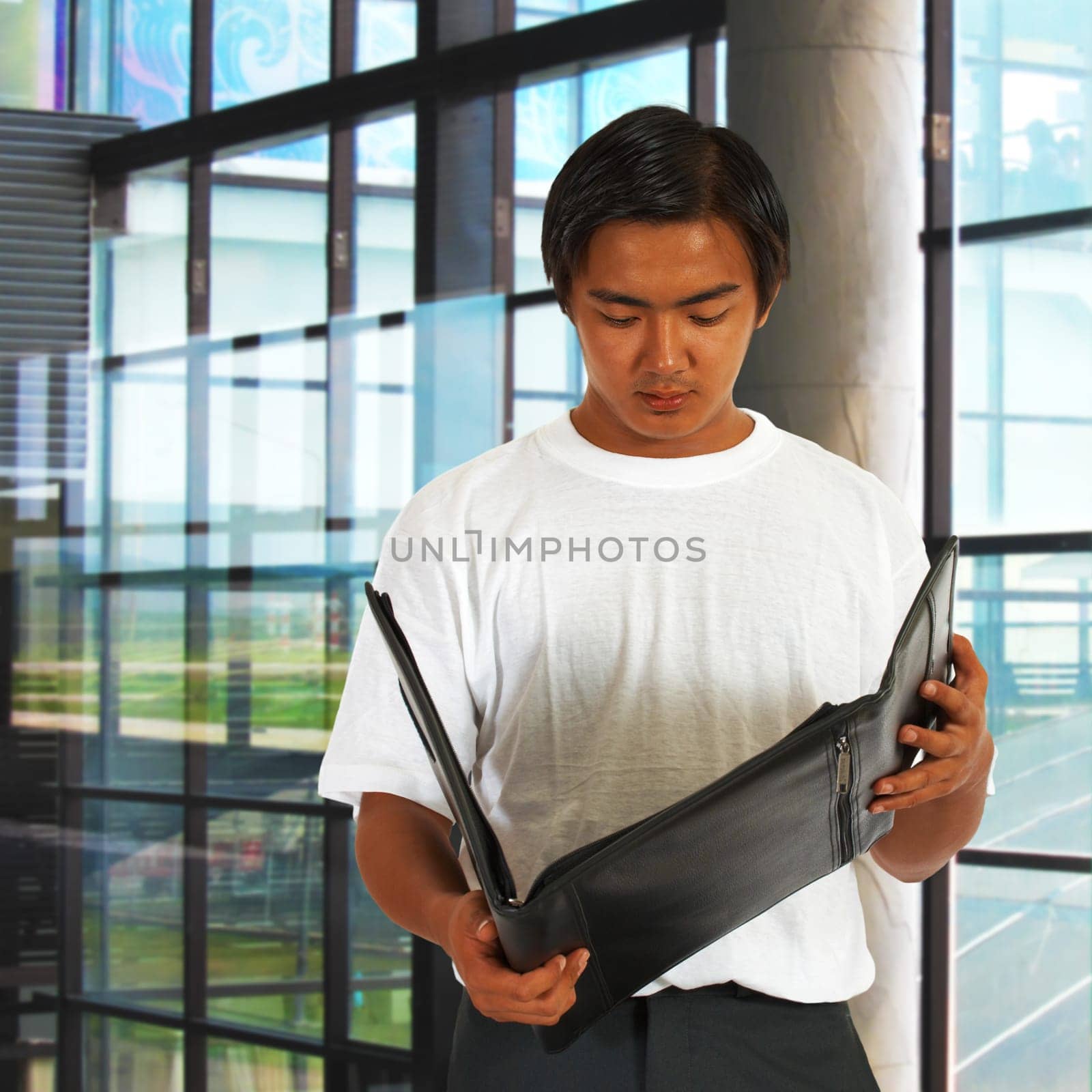Office Worker Standing By The Window And Checking Notes In A Leather Folder