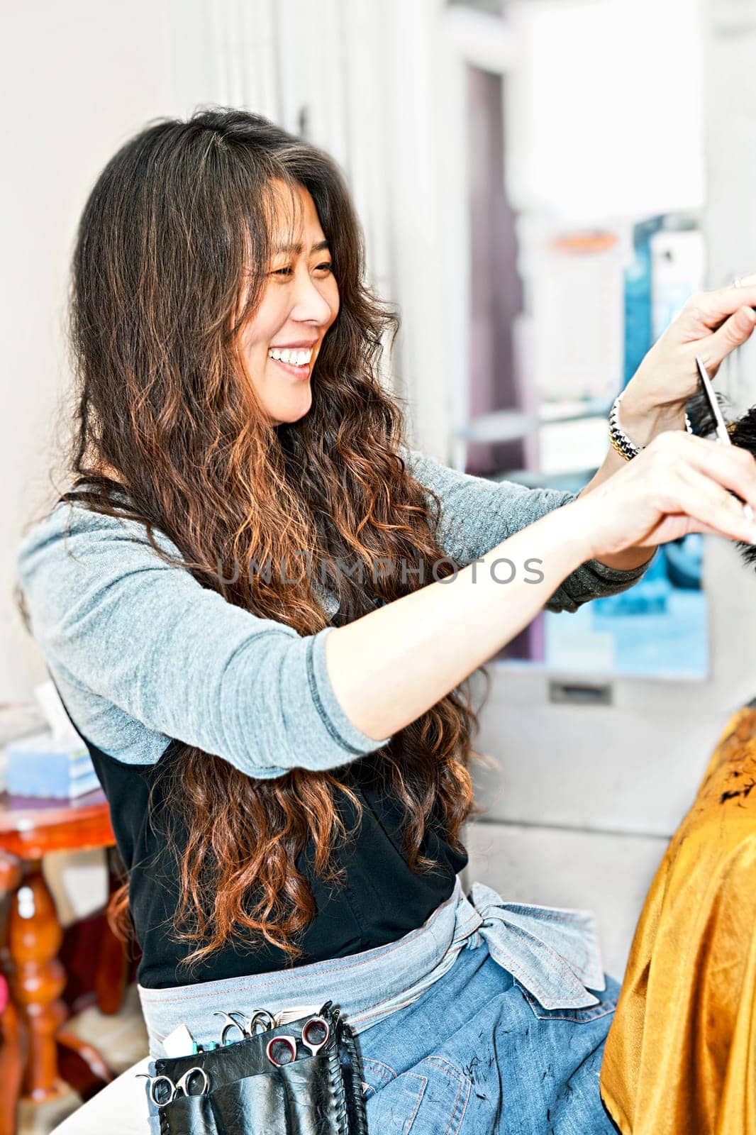 Happy hairdresser cutting hair in her salon