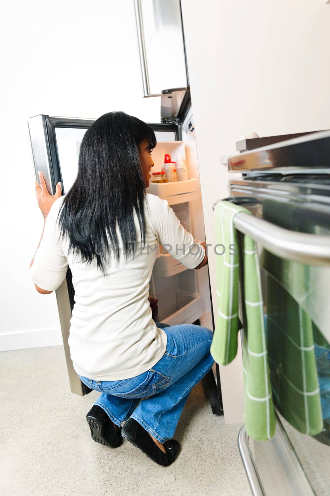 Black woman looking in fridge of modern kitchen interior