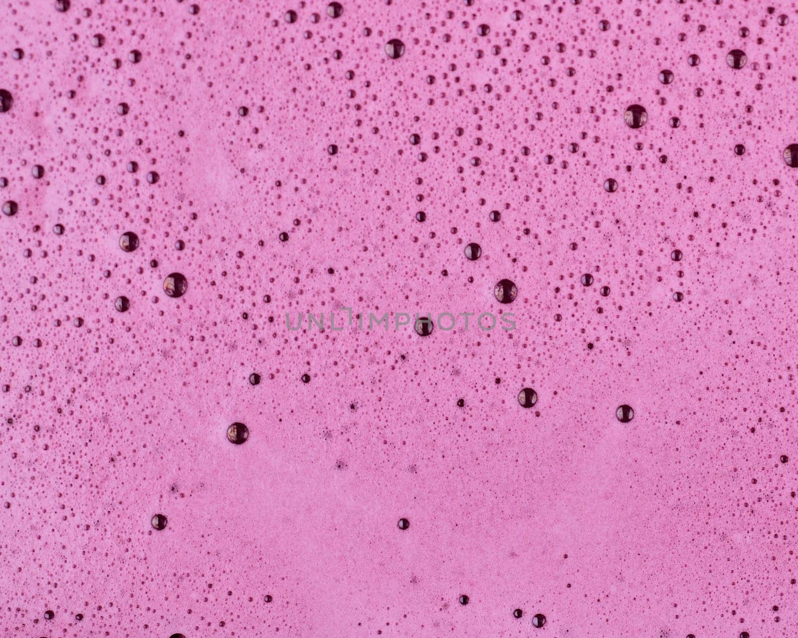 Close-up of blueberry juice bubbles on top of organic blueberry juice.