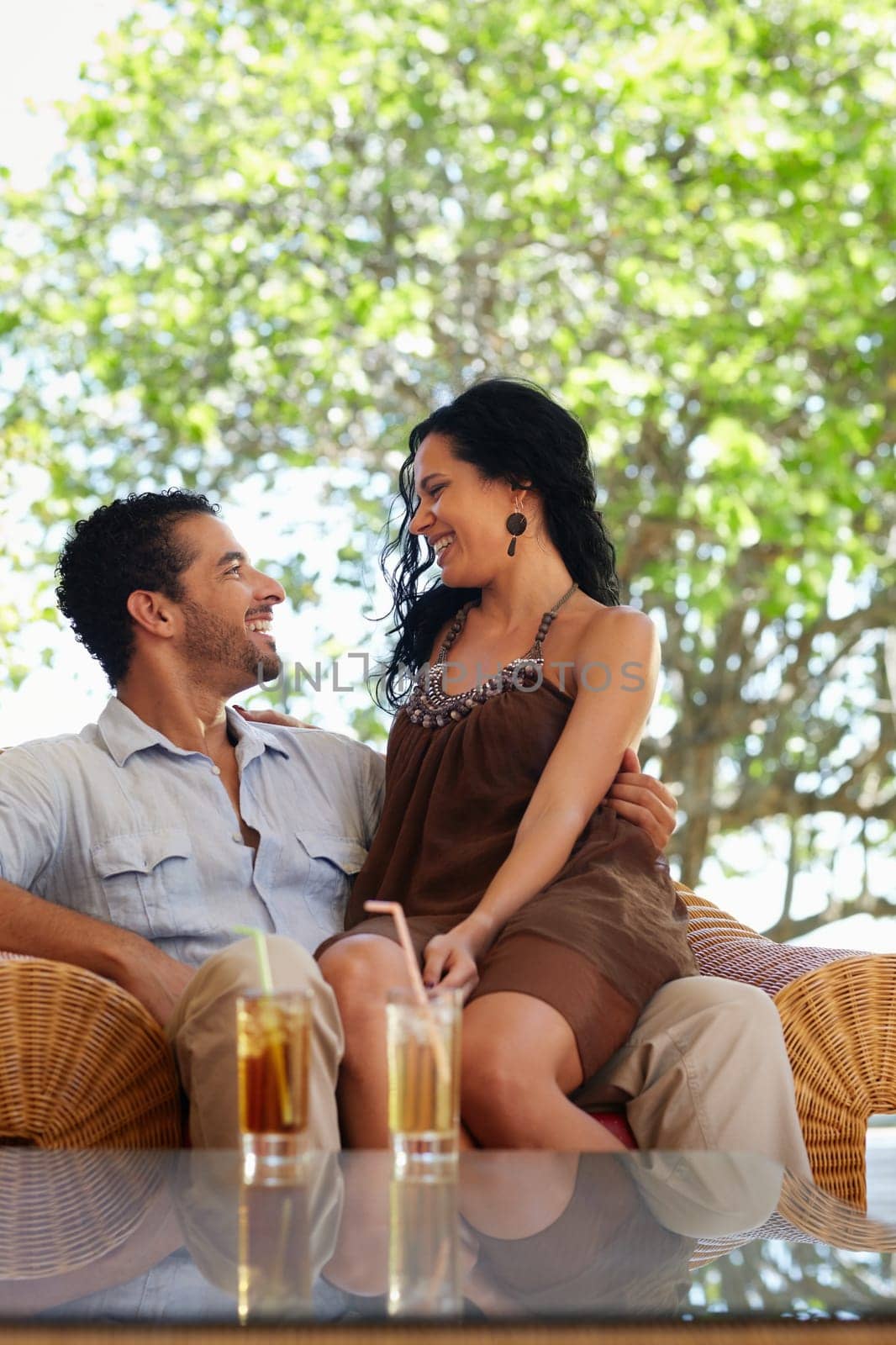 honeymoon: young just married hispanic couple sitting on armchair in hotel bar. Vertical shape, copy space