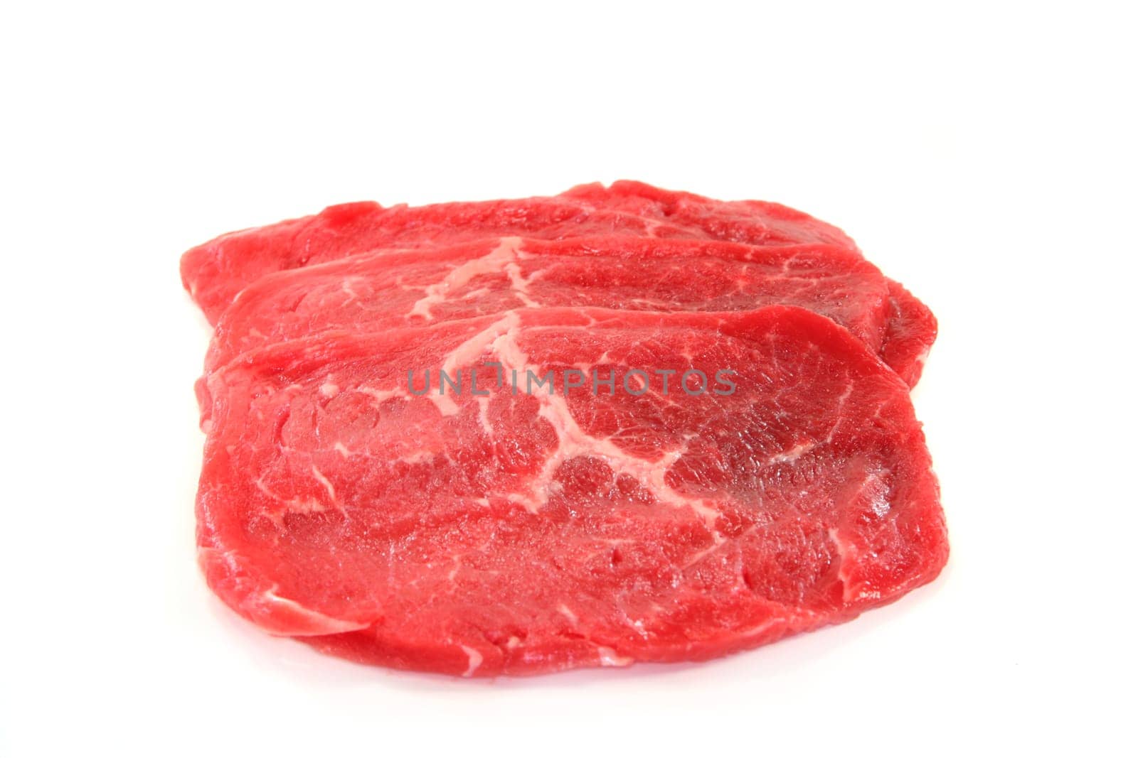 Three raw beef minute steaks against white background