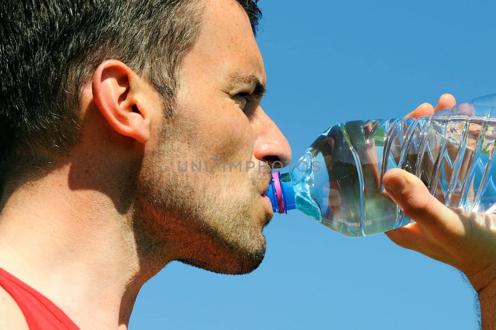 Man is drinking water against blue sky
