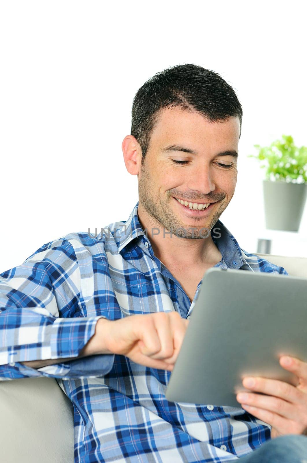 attractive relaxed and positive man is surfing on his tablet