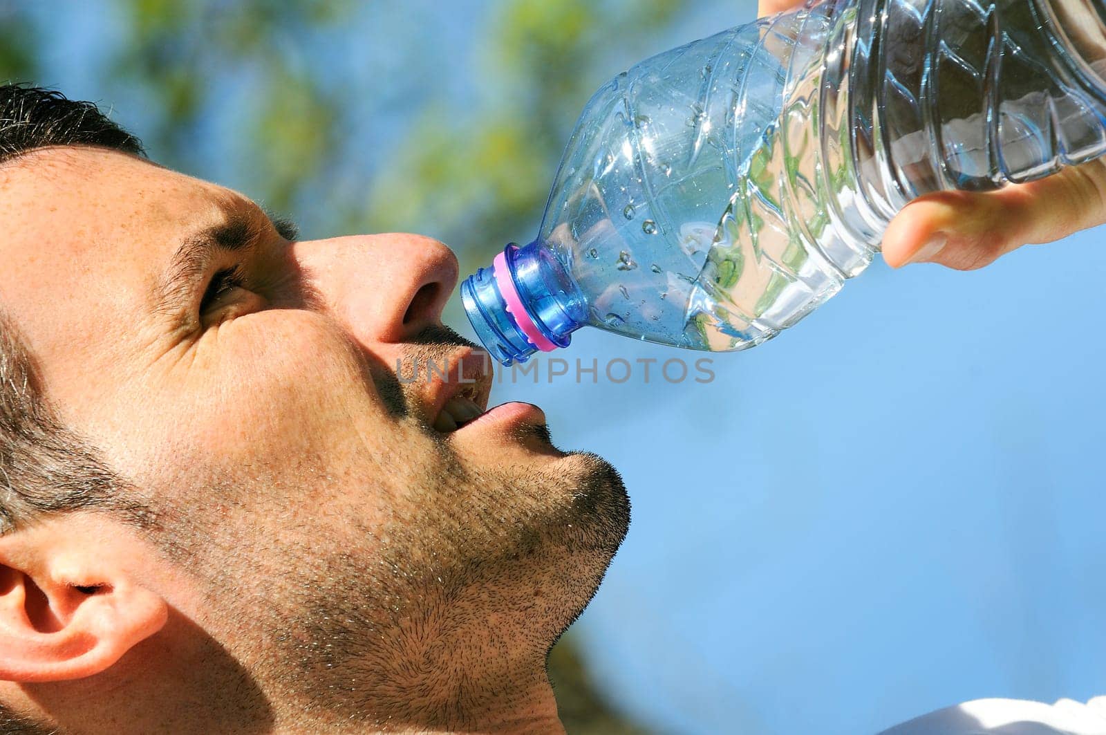 Man is drinking water against a natural background