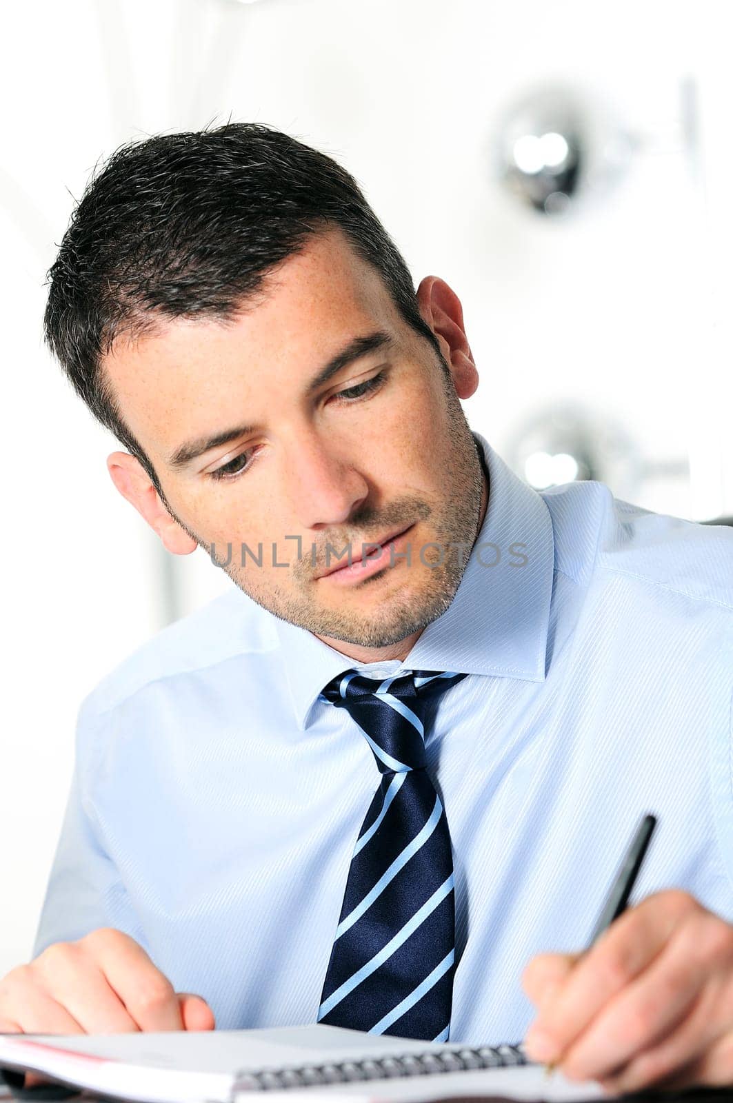 An attractive business man is writing on a paper