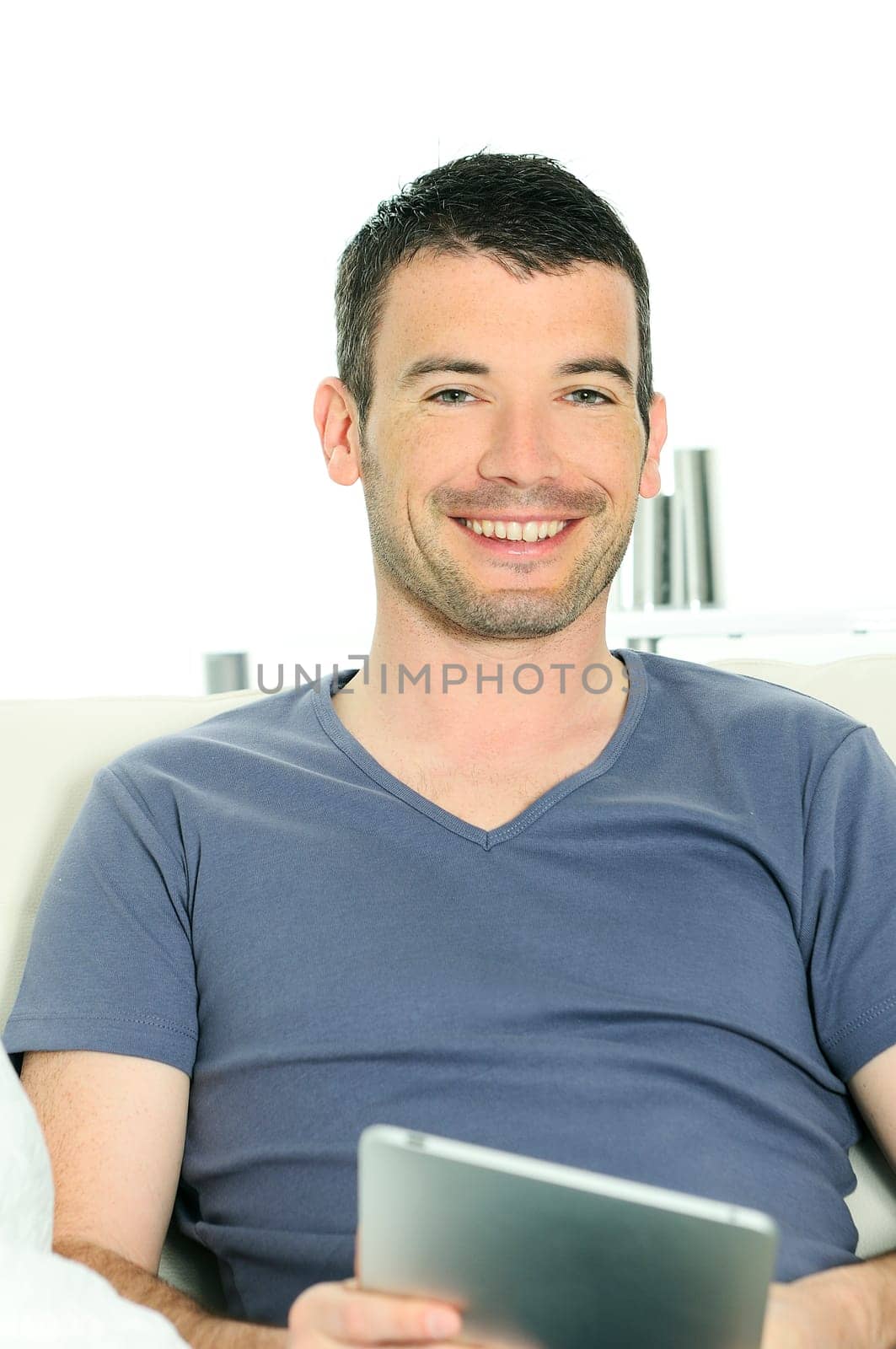 attractive relaxed and positive man is surfing on his tablet