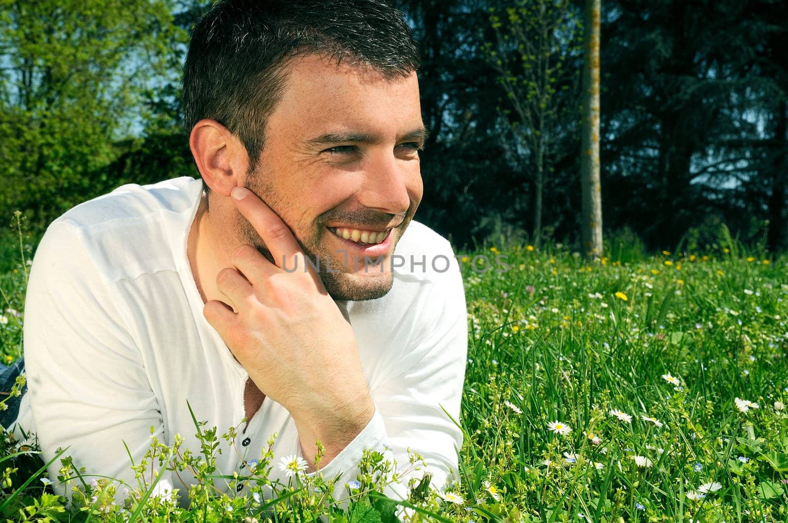 An attractive and cheerful man lying in the park