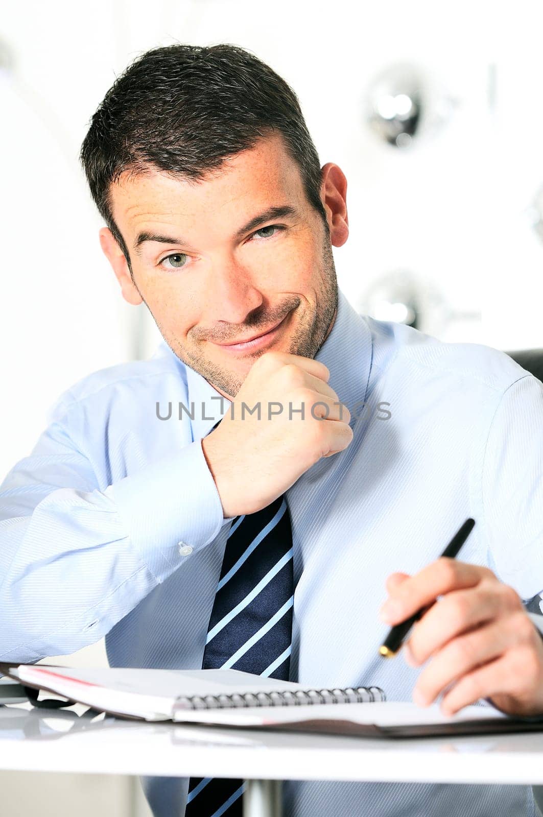 An attractive business man is writing on a paper