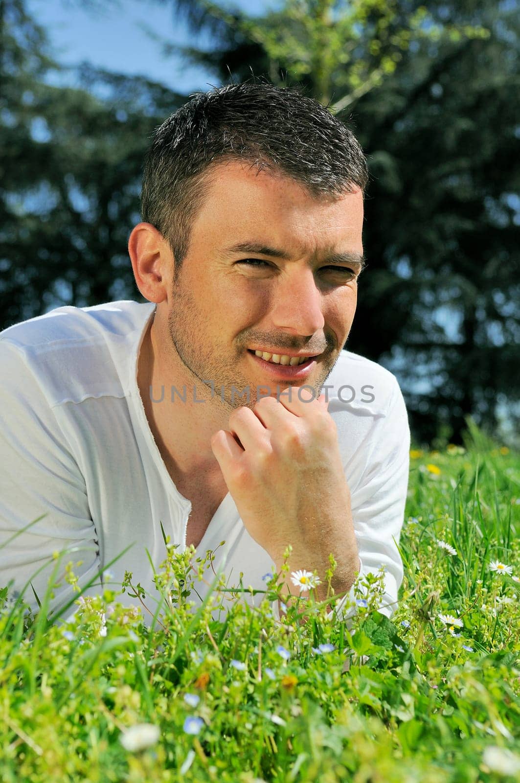 An attractive and cheerful man lying in the park